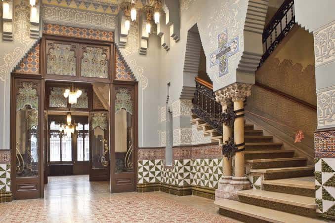 Interior del vestíbulo con escalera de mármol y decoración de azulejos