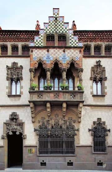 Fachada de la Casa Coll i Regàs con balcones floridos y almenas decoradas
