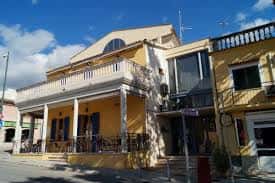 Fachada exterior de Sa Societat en Calvià, mostrando su arquitectura tradicional con balcones y columnas bajo un cielo azul