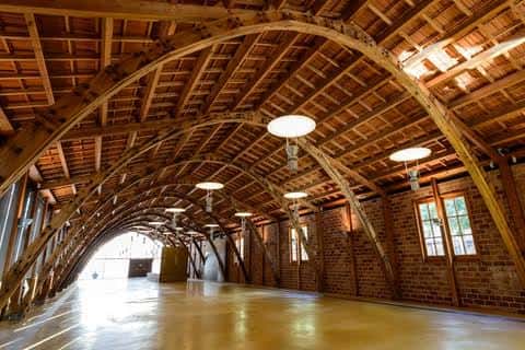 Interior de la Nau Gaudí mostrando su estructura de arcos de madera y suelo pulido, ideal para eventos