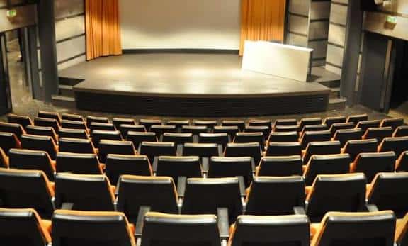 Interior del auditorio con escenario y butacas negras