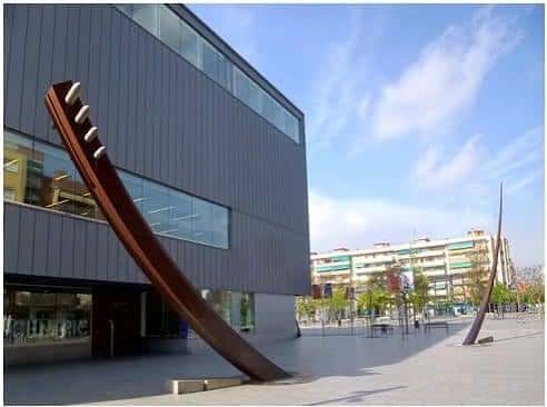 Fachada exterior moderna de la biblioteca con escultura artística en el patio