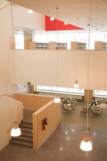 Interior luminoso de la biblioteca con zonas de lectura, escaleras y diseño abierto