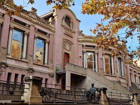 Vista lateral del edificio con escalinata y árboles de otoño en primer plano