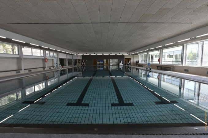 Pista de natación interior con carriles marcados y grandes ventanales laterales