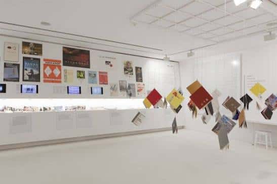 Interior del centro de arte con exposición de carteles y elementos suspendidos