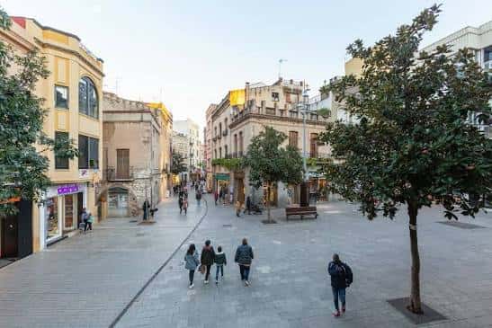 Vista panorámica de la plaza con peatones caminando entre edificios históricos