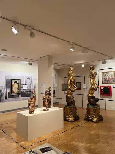 Sala de exposiciones con esculturas doradas y obras en las paredes