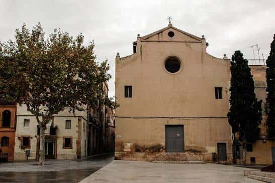 Fachada lateral de la iglesia con árboles y cielo nublado