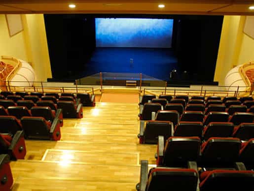 Interior del auditorio del Teatro Palenque con butacas rojas y escenario iluminado