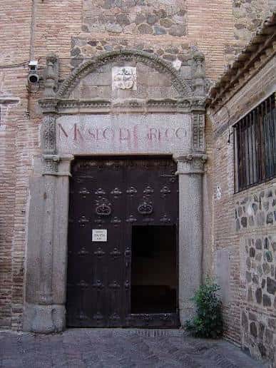 Entrada principal del Museo del Greco con puerta de madera y escudo
