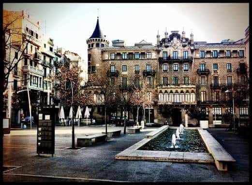 Vista panorámica de la plaza con la fuente central y edificios históricos al atardecer