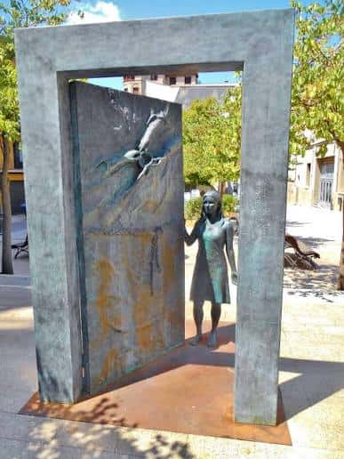 Monumento a l'Acollida con la estatua de la mujer y la puerta simbólica