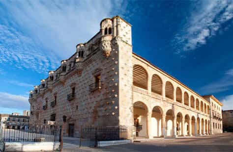 Fachada lateral del palacio con galería de arcos bajo cielo azul