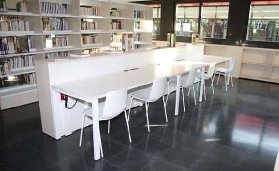 Área de estudio con largas mesas blancas y sillas modernas