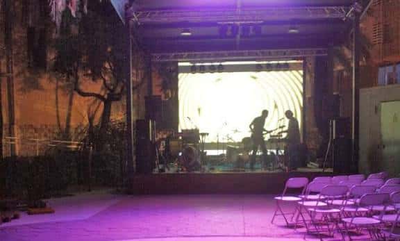 Escenario del Espai Jove La Palmera iluminado con luces de colores durante un concierto nocturno