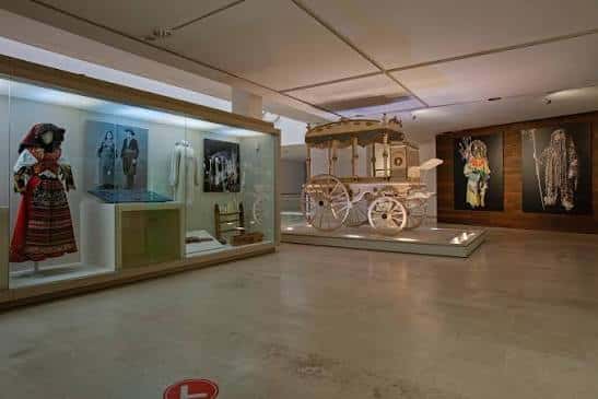Sala de exposiciones con carroza histórica y trajes tradicionales