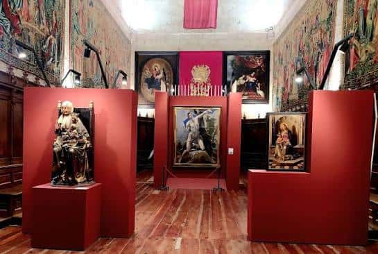Sala de arte sacro con pinturas, tapices y esculturas enmarcadas