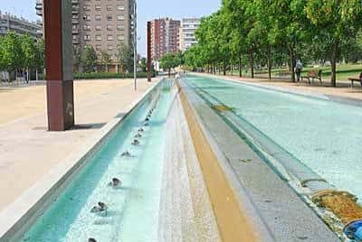 Canal de agua en el parque con fuentes y bancos a los lados
