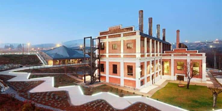 Vista diurna del complejo con senderos iluminados y arquitectura de ladrillo y hormigón