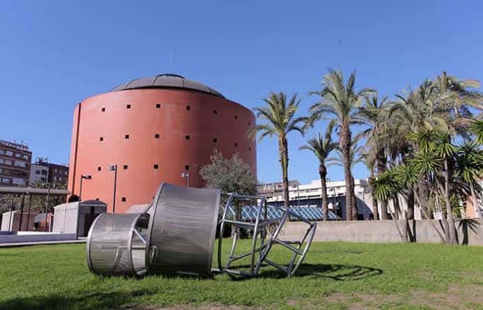 Vista exterior del Museo MEIAC con su característica fachada cilíndrica de ladrillo y esculturas en el jardín