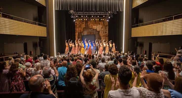 Interior del teatro durante una función con escenario iluminado y público en butacas