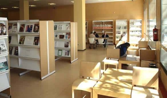 Interior de la biblioteca con zonas de lectura, estanterías y mesas para usuarios