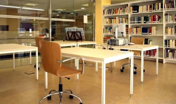Área de estudio con escritorios, sillas ergonómicas y estanterías de libros en la Biblioteca de Cáceres