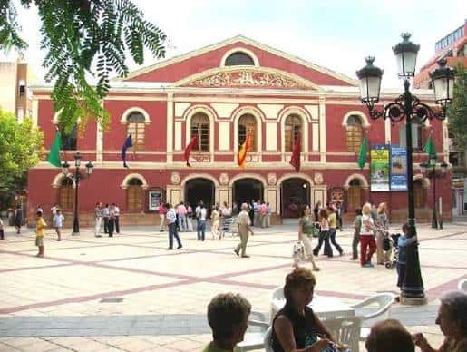 Fachada principal del Teatro Guerra en la plaza durante el día con banderas