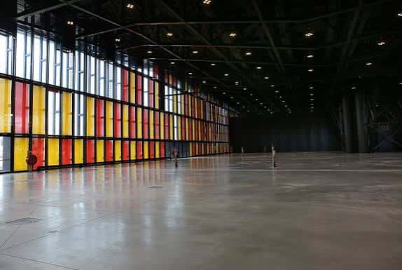 Interior del salón de exposiciones con suelo de hormigón y paredes de cristal coloreado