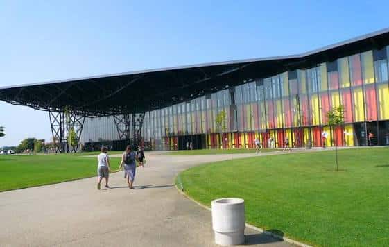 Entrada principal del Palacio de Congresos con personas caminando por el jardín