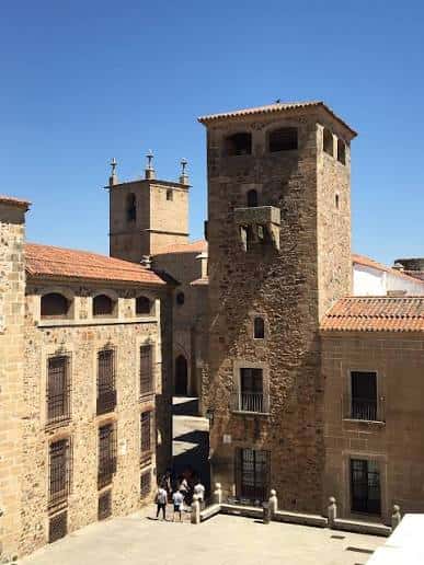Torre de la Merced y fachadas de piedra de la plaza bajo cielo azul