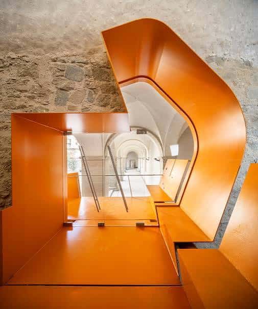 Detalle arquitectónico interior con elementos naranjas y pasillos curvos