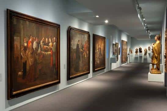 Galería de pintura barroca con obras de gran formato y esculturas en el fondo