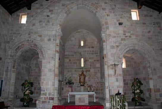 Interior de la iglesia mostrando el altar y arcos románicos