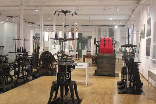 Interior del museo con máquinas de punto antiguas expuestas en sala iluminada
