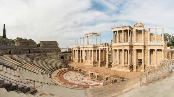 Vista panorámica del Teatro Romano de Mérida con gradas y escenario bajo cielo parcialmente nublado