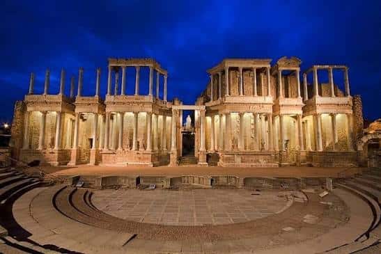 Teatro Romano de Mérida iluminado por la noche con cielo azul oscuro y luces cálidas en las columnas