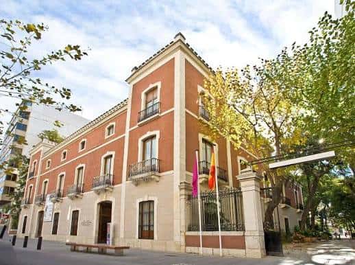 Vista exterior de la Casa de Cultura Marqués de González de Quirós con fachada de ladrillo y banderas