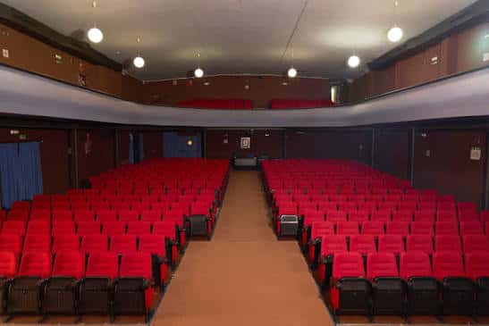 Interior del auditorio con butacas rojas y escenario