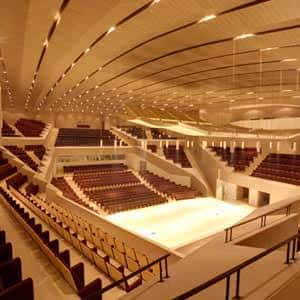 Interior del auditorio con escenario vacío y gradas curvas iluminadas