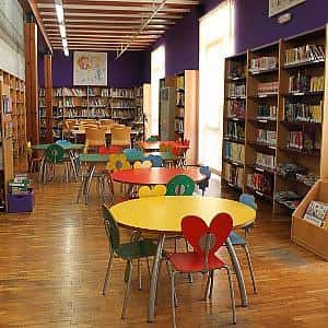 Sala infantil de la biblioteca con mesas y sillas coloridas, ideal para eventos familiares