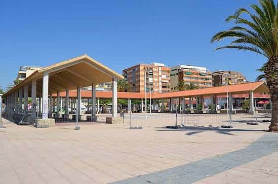 Pérgola de madera instalada en la plaza con palmeras y cielo despejado