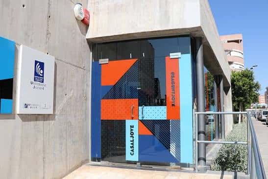 Entrada principal del Casal Jove con puerta de cristal y señalización institucional