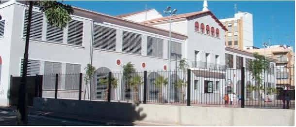 Fachada lateral del edificio escolar con valla perimetral