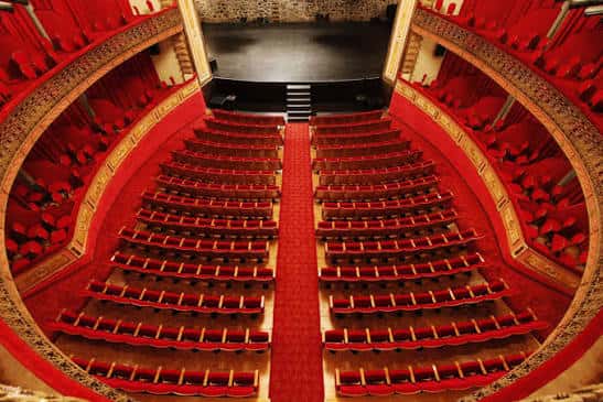 Vista panorámica del interior del Gran Teatro de Cáceres mostrando las butacas rojas y los palcos