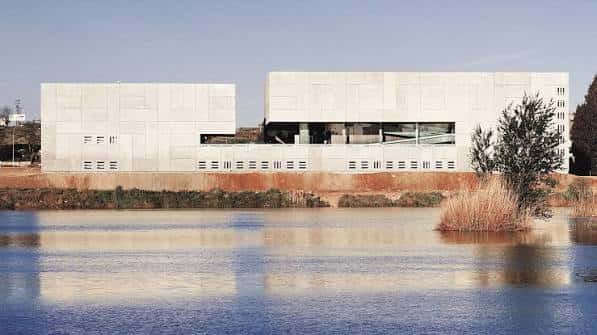 Fachada del Palacio de Congresos reflejada en el agua, con diseño arquitectónico moderno