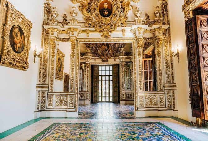Sala de trono con decoración barroca dorada y suelo de azulejos