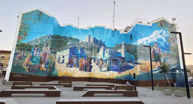 Vista amplia de la Plaza de Arriba en Elda con el mural histórico y bancos de diseño moderno