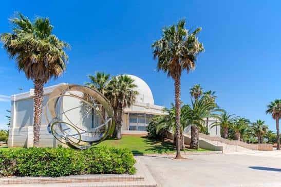 Exterior del Planetario con escultura metálica en primer plano y entorno ajardinado